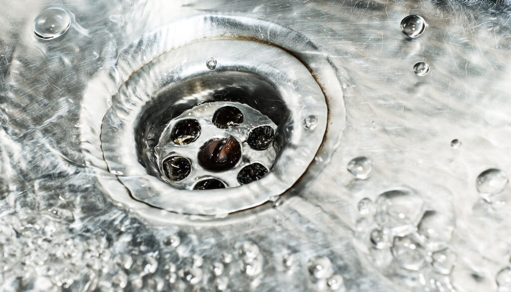 Stainless steel sink plug hole close up with water