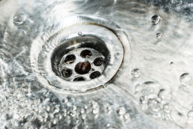 Stainless steel sink plug hole close up with water