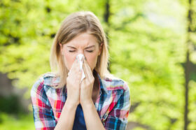 Woman with allergy symptom blowing nose