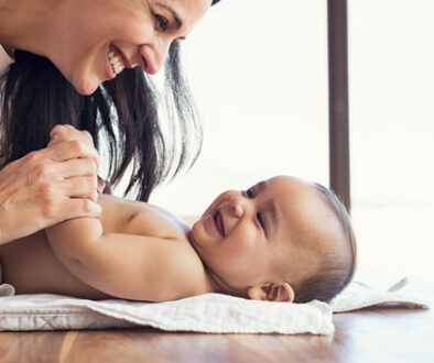 Happy mother playing with baby while changing his diaper. Smilin