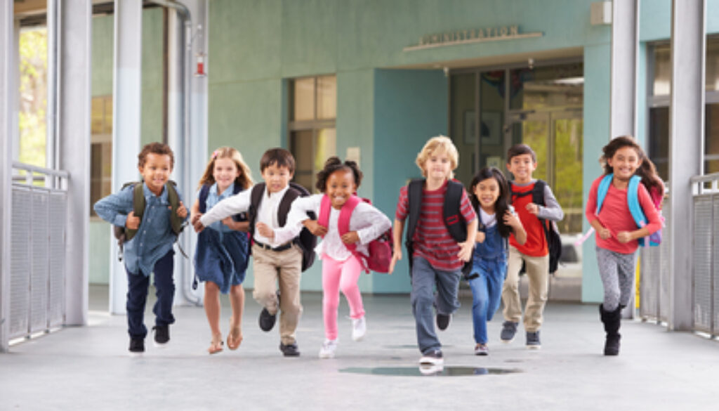 Group of elementary school kids running in a school corridor