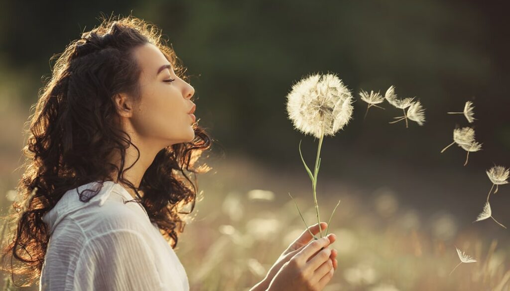 woman-blowing-dandelion-in-field-without-allergies