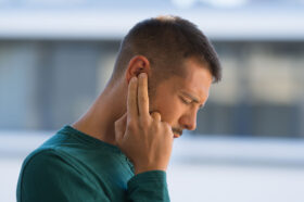A Man Holding Two Fingers to His Ear While Dealing with Crackling Sounds in Ear