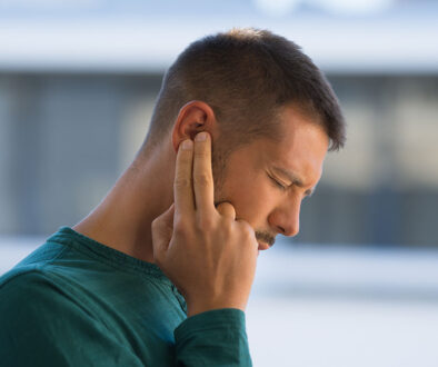 A Man Holding Two Fingers to His Ear While Dealing with Crackling Sounds in Ear