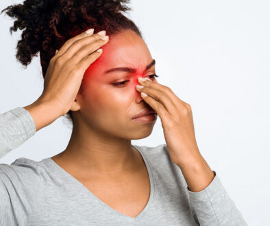 An African American Woman Holding Her Nose and Head That Are Highlighted in Red Can Chronic Sinusitis Affect Your Whole Body